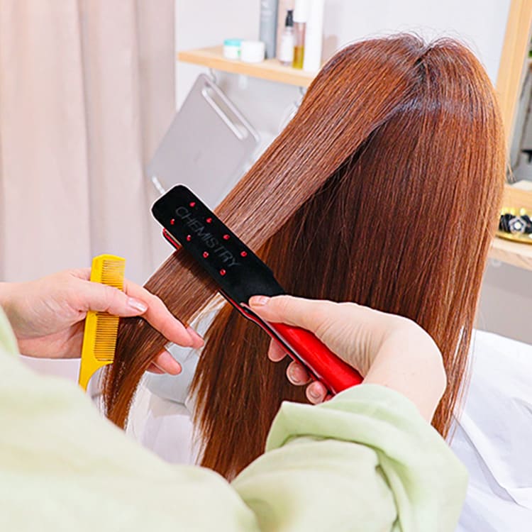 ミディアムヘアにヘアアイロンをあてている様子